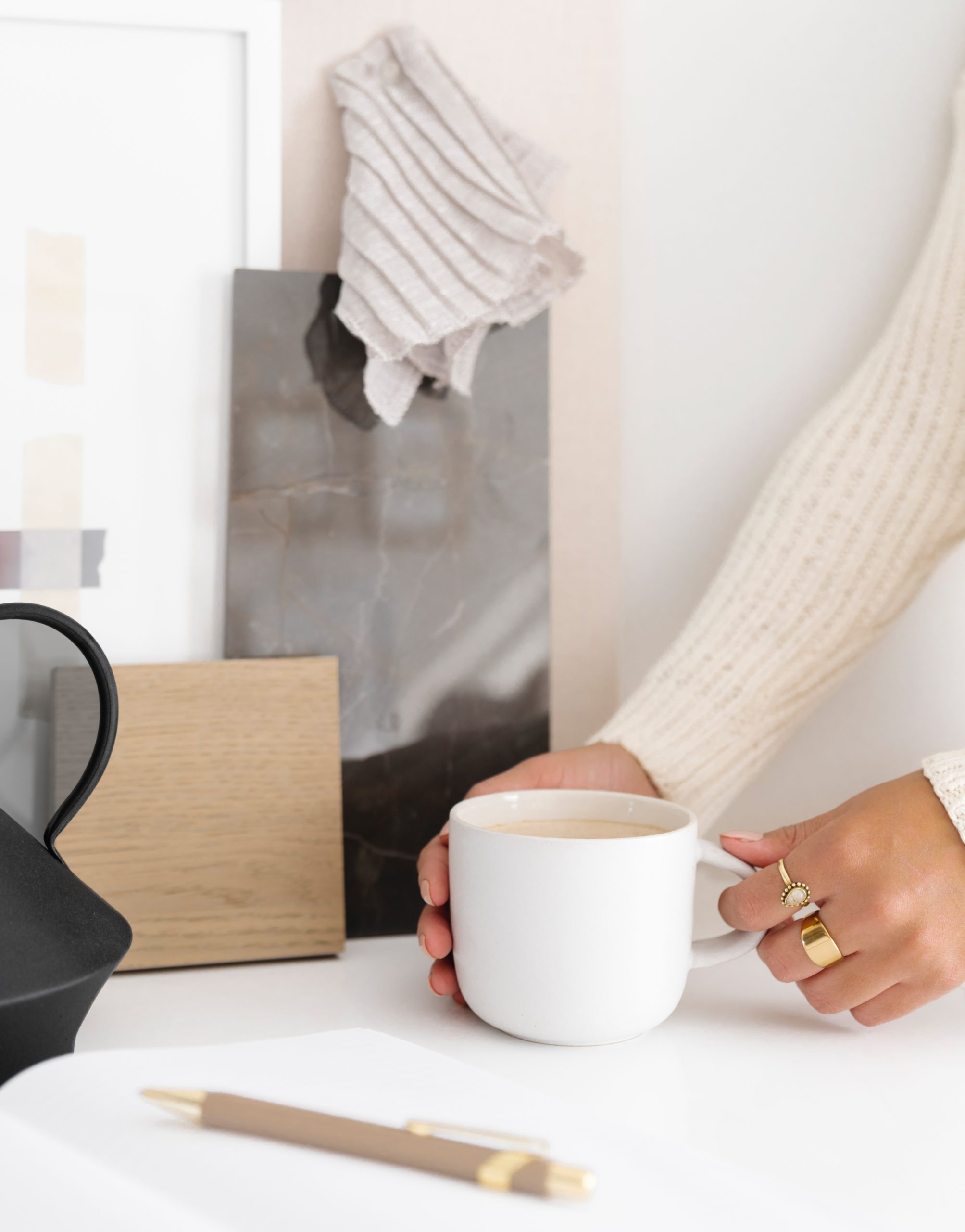 woman holding a cup of coffee that is sitting on a white counter
