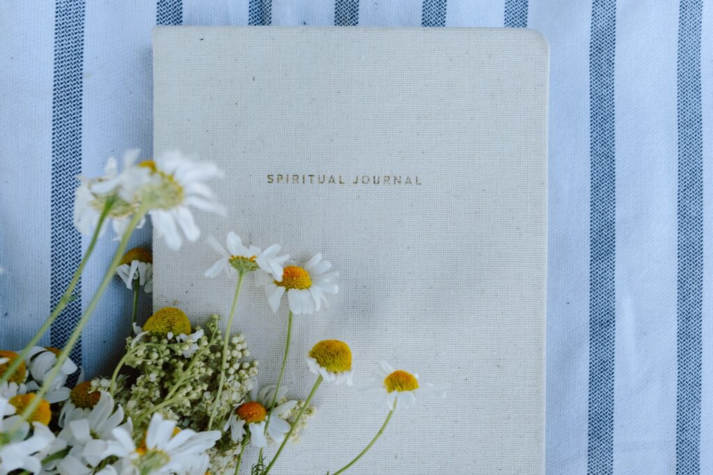 Picture of a white spiritual journal with some daisies on top.