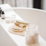 White bathtub with essential oils and bath accessories on placed on a bathtub caddy