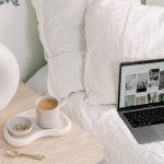 laptop on a bed with coffee on the nightstand