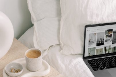 laptop on a bed with coffee on the nightstand