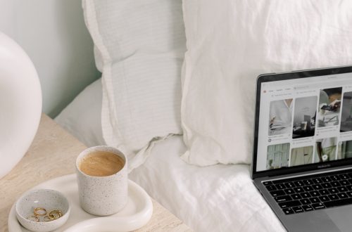 laptop on a bed with coffee on the nightstand