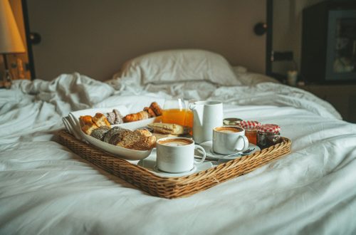 pastries and coffee on a tray placed on top of a bed