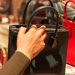 a lady's hand holding a black back in a department store with lots of handbags
