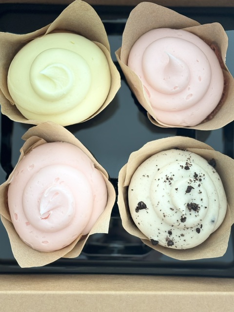 Four cupcakes from the Magnolia Baking Co.: Two Strawberries N' Cream, one Cookies 'N' Cream, and one Lemon Lavender.