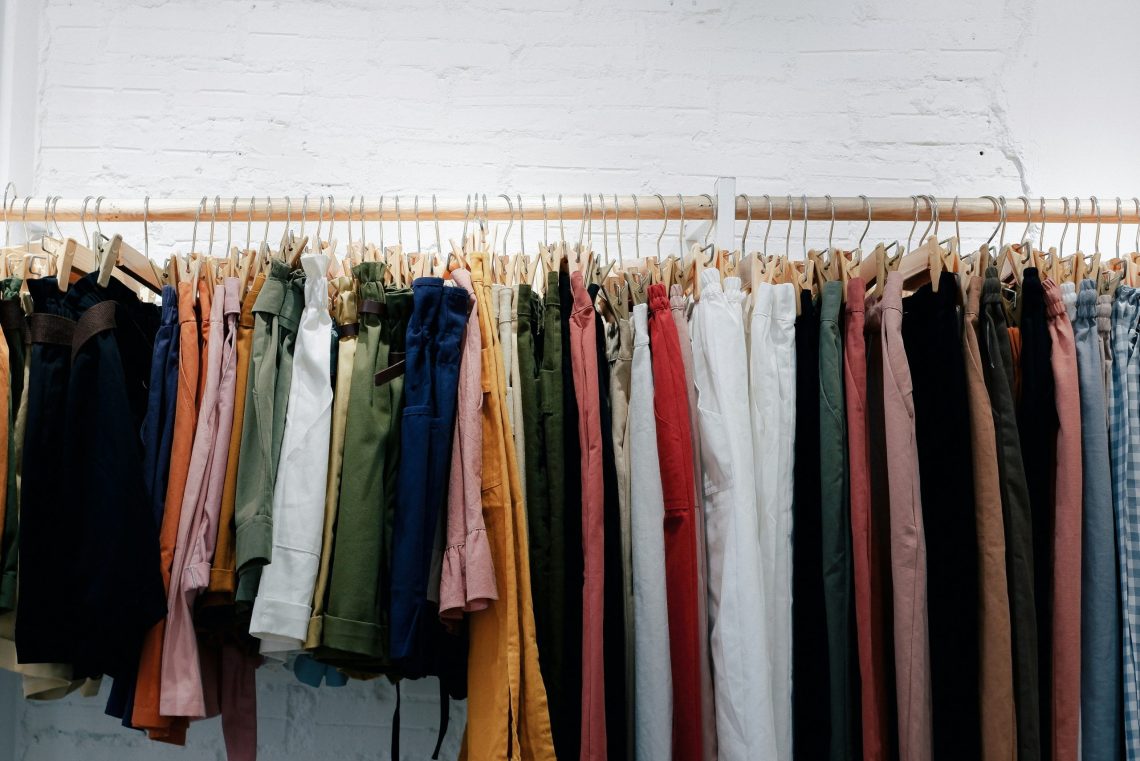 Clothing rack displaying colorful women's trousers and shorts in neutral and classic colors for building a timeless wardrobe.