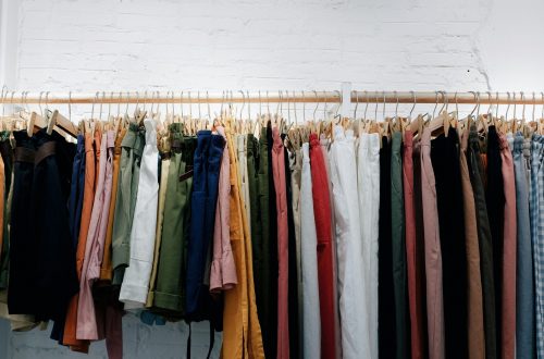 Clothing rack displaying colorful women's trousers and shorts in neutral and classic colors for building a timeless wardrobe.