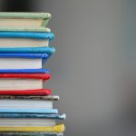 Stack of colorful hardcover books with copy space on a gray background.