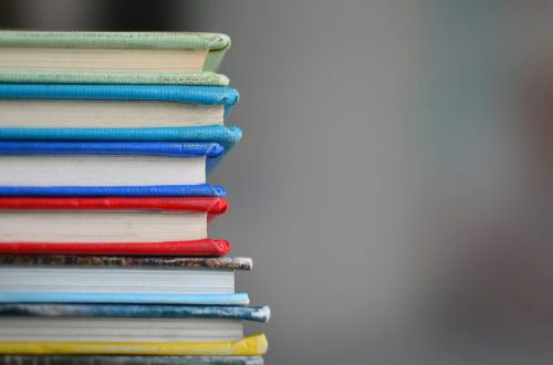 Stack of colorful hardcover books with copy space on a gray background.