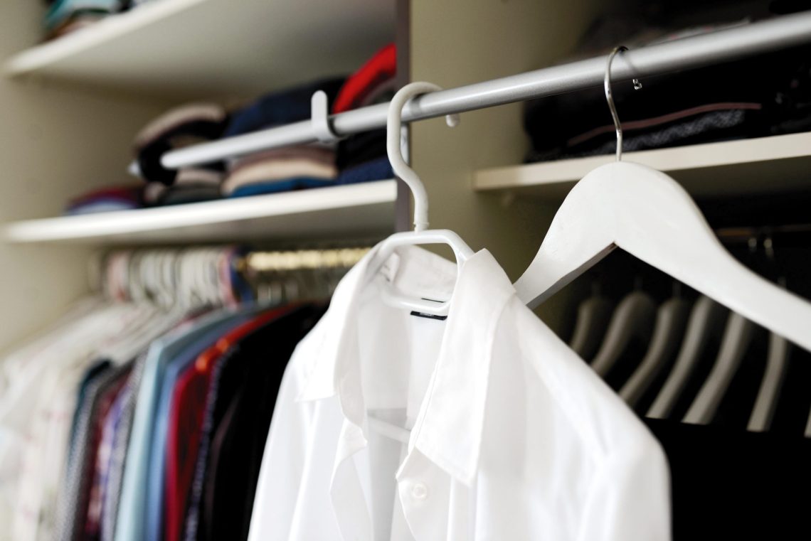 Picture of inside of a closet with a white collared shirt being prominently featured.