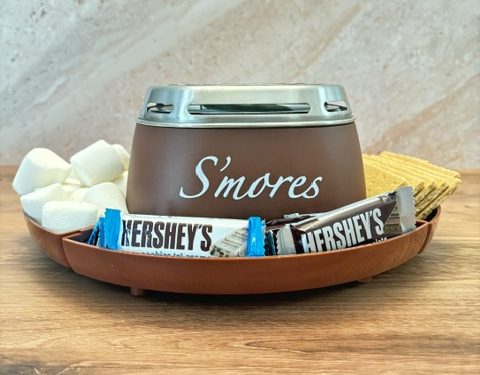 S’mores maker surrounded by marshmallows, graham crackers and Hershey’s chocolate bars for a family movie night.