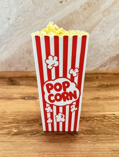 Red and white striped popcorn box filled with popcorn for a family movie night.